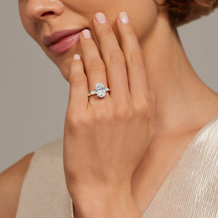 Three stone diamond engagement ring in yellow gold worn on the hand